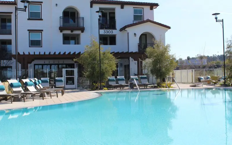 A pool with chairs and a building in the background