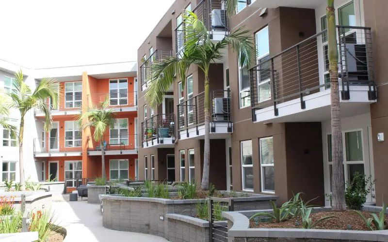 A row of apartment buildings with palm trees in the background.