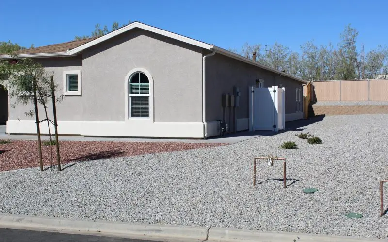 A house with gravel and a driveway in front of it.