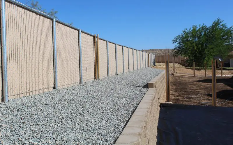 A concrete wall with gravel and rocks on the side.