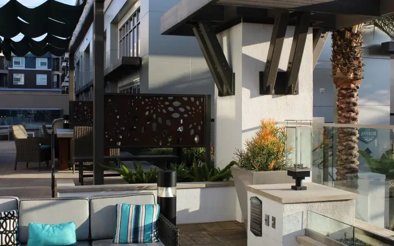 A patio with a table and chairs, potted plants and a bench.