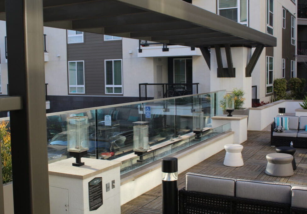 A patio with tables and chairs, benches, and a glass railing.