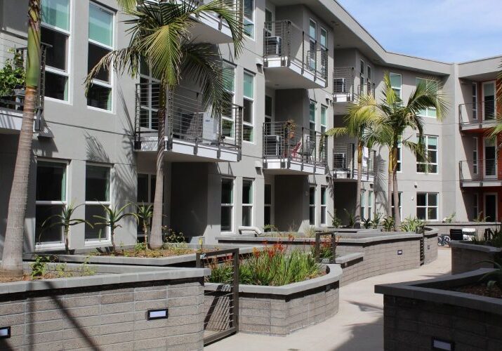 A building with palm trees and concrete planters.