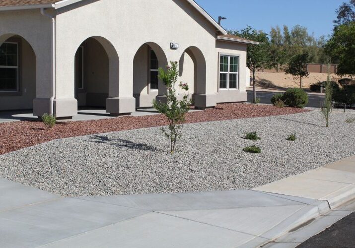 A house with gravel and concrete driveway in front of it.